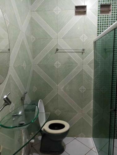 a bathroom with a toilet and a glass shower at Casa para Reveillon - cururupe in Ilhéus