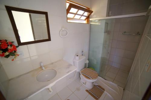 a bathroom with a sink and a toilet and a mirror at Pousada Acácias dos Corais in Cabo de Santo Agostinho