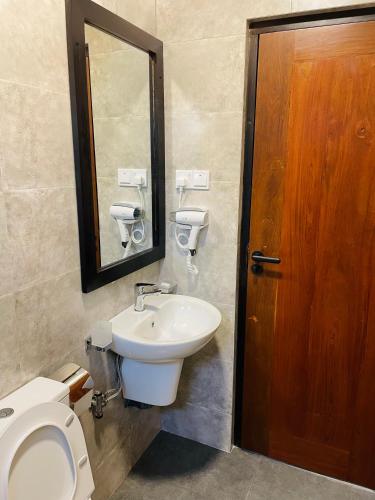 a bathroom with a toilet and a sink and a mirror at The Urban Escape in Matara