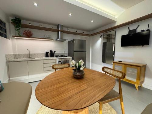 a kitchen with a wooden table and some chairs at Praia do Rosa Park Studio in Guarapari