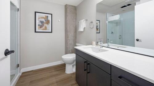 a white bathroom with a toilet and a sink at Landing Modern Studio Rooftop Lounge Gym in Englewood