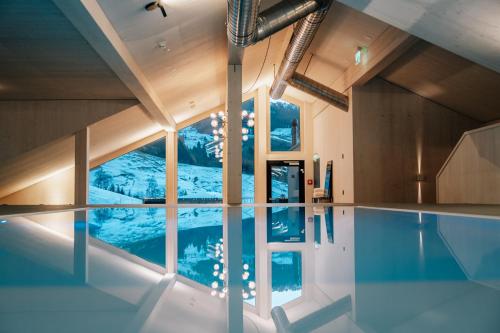 einen Pool mit Blick auf einen verschneiten Berg in der Unterkunft Roggenstock Lodge in Oberiberg