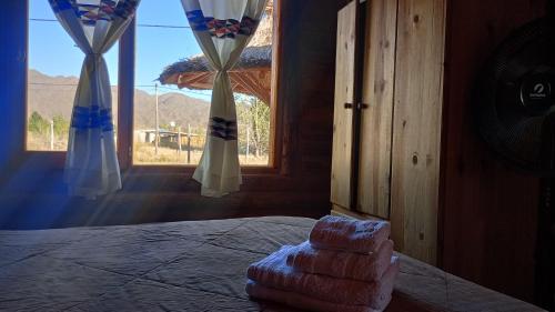 un groupe de serviettes posées sur un lit dans une chambre avec une fenêtre dans l'établissement Cabañas Angualasto, à Uspallata