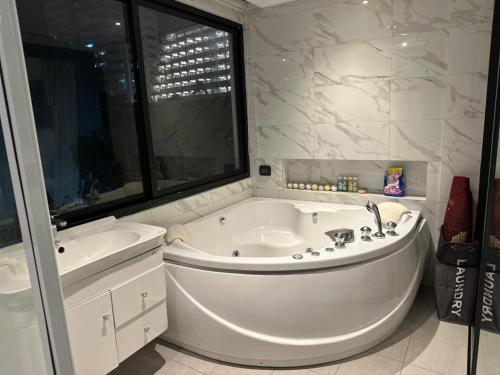 a white bathroom with a tub and a sink at Patong Condo Tub, Roof Pool & 2-min to Beach in Patong Beach