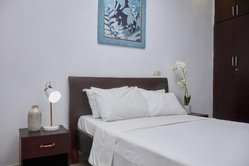 ein Schlafzimmer mit einem Bett mit weißen Laken und einem blauen Bild in der Unterkunft Résidences Riverside Abidjan in Abidjan