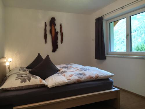 Bett in einem Zimmer mit Fenster in der Unterkunft Haus Margreiter in Sankt Leonhard im Pitztal