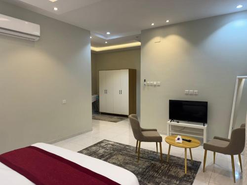 een slaapkamer met een bed en een tv en stoelen bij Holiday Home Al Taif Al Wisam in Taif