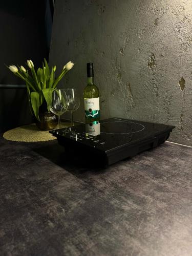 una bottiglia di vino appoggiata su un vassoio con bicchieri da vino di Tyla Dviese a Bendoriai