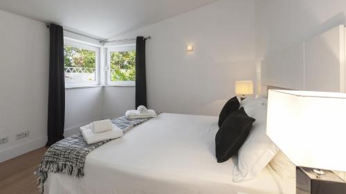 una camera da letto bianca con un letto grande e una finestra di Casa dos Pelargónios a Luz