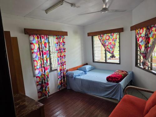 een kleine kamer met een bed en twee ramen bij Tunu House in Viseisei