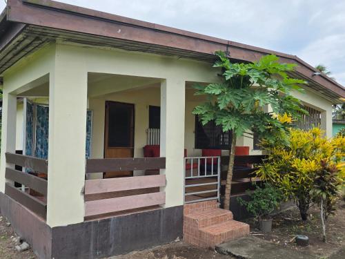 een klein huis met een veranda en een boom bij Tunu House in Viseisei
