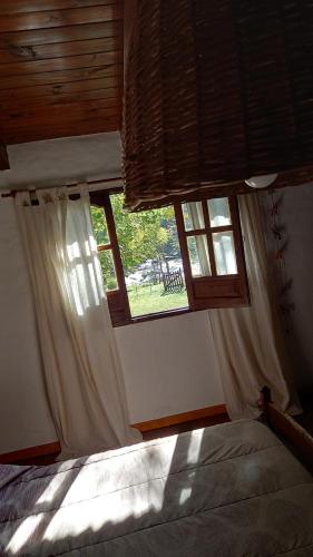 a bedroom with a bed and two windows at la riviere in Alta Gracia