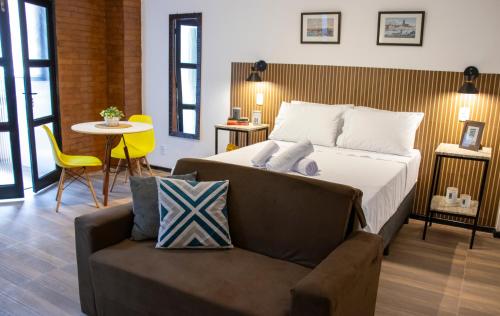 a bedroom with a bed and a chair and a table at Centro Histórico com Garagem - Studio Petrópolis in Petrópolis