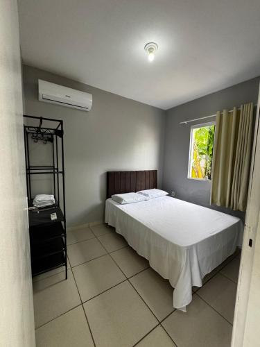 a bedroom with a white bed and a window at Casa em Imbituba SC, perto das Praias e Lagoa in Imbituba
