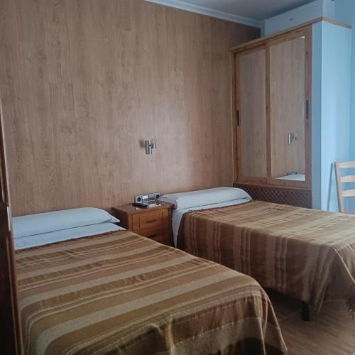 a room with two beds and a small cabinet at Hostal Los Palancares in Fuentes