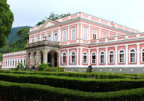 een groot roze gebouw met een tuin ervoor bij Studio Petrópolis - Centro Histórico com Garagem in Petrópolis