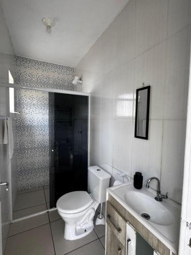 a white bathroom with a toilet and a sink at Casa em Imbituba SC, perto das Praias e Lagoa in Imbituba
