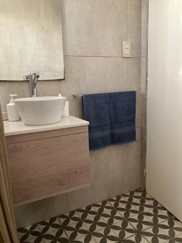 een badkamer met een wastafel en een blauwe handdoek bij Balcarce Apartment in Vuelta del Paraguayo