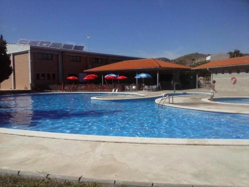 een groot blauw zwembad met rode parasols bij Ramon del Xalet in Ibars de Noguera