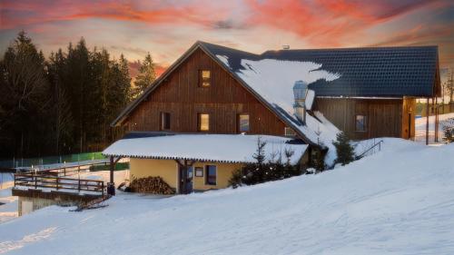 un fienile nella neve con un tramonto di Penzion Čekanka a Strážné