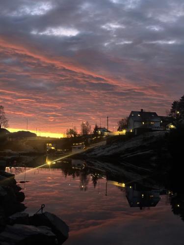 een zonsondergang boven een waterlichaam met een huis bij Aurora Bliss - Fjordfront Jacuzzi & Sauna near Bergen in Askøy