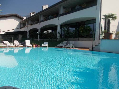 a large swimming pool with chairs and a building at Hotel Laura Christina in Malcesine