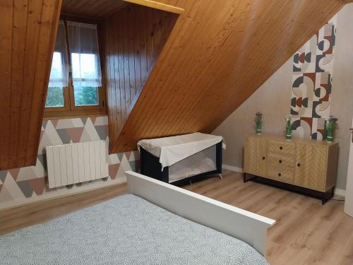 Cette chambre mansardée dispose d'un lit et de plafonds en bois. dans l'établissement Country apartment, à Orgelet