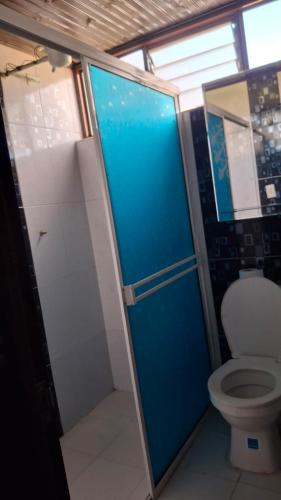 a bathroom with a toilet and a blue shower stall at Cabaña el Rincon Del Lago in Paipa