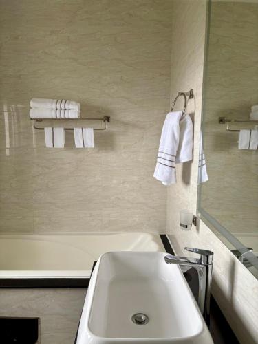 a bathroom with a sink and a tub and towels at The Gentle Nest in Trevallyn