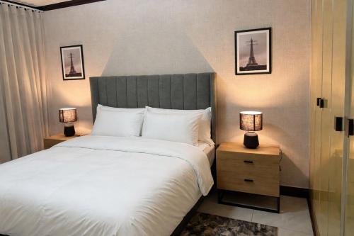 a bedroom with a large white bed with two lamps at The Gentle Nest in Trevallyn