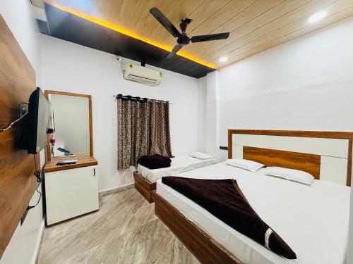 a bedroom with two beds and a tv and a mirror at Hotel Tathastu Inn in Ujjain