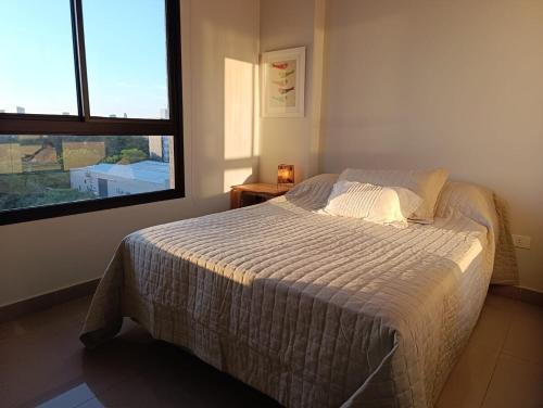 een slaapkamer met een bed en een groot raam bij Departamento con excelente ubicación in Luque