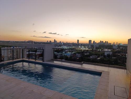 een zwembad op het dak op een gebouw met een skyline van de stad bij Departamento con excelente ubicación in Luque