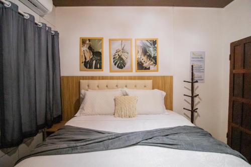 a bedroom with a bed with three pictures on the wall at Pousada da Leide in Fernando de Noronha