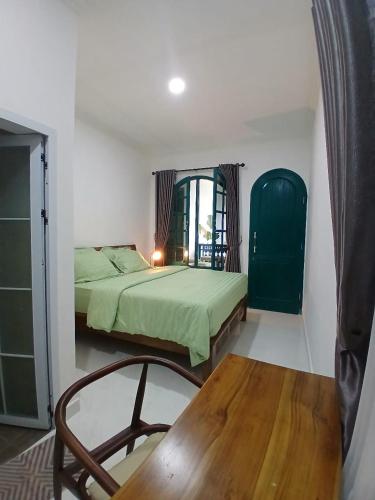 a bedroom with a green bed and a wooden table at Omah Barepan Temple View in Borobudur
