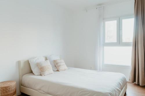 un letto bianco con cuscini bianchi e una finestra di Le Quai 06 a Le Havre