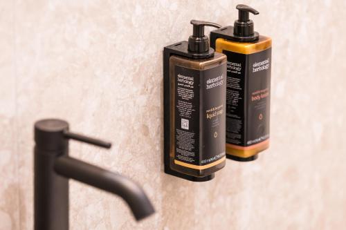 two bottles ofodorizers on a wall next to a sink at Mercure Bucharest Cantemir in Bucharest