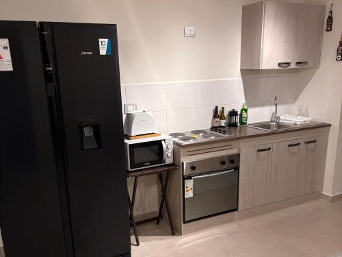 een keuken met een zwarte koelkast en een magnetron bij Comodo y cercano a la playa in Coquimbo