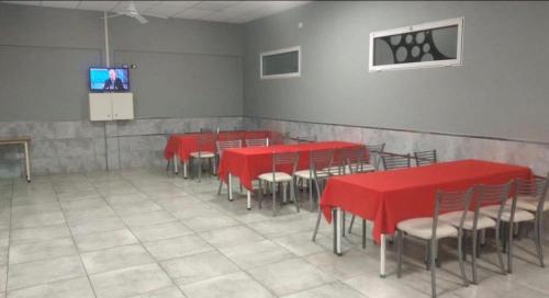 Zimmer mit roten Tischen und Stühlen und einem Bildschirm in der Unterkunft Quinta Altos del Prado in San Nicolás de los Arroyos