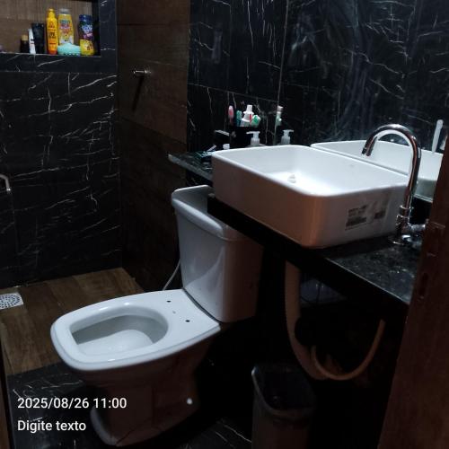 a bathroom with a white toilet and a sink at Aconchego particular in Guaramiranga