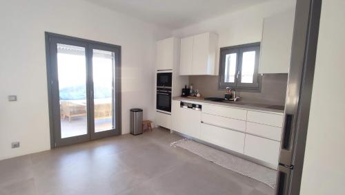 une cuisine avec des placards blancs et une grande fenêtre dans l'établissement Villa Glaronisi Kea, à Otziás