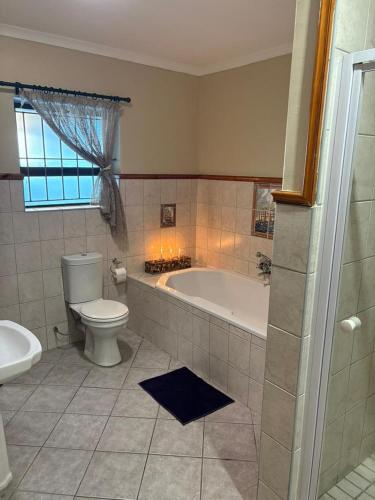 a bathroom with a tub and a toilet and a sink at Waaigras in Brackenfell