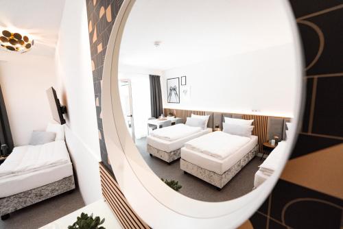 a hotel room with two beds and a mirror at Das Naturlich - Ruhiges Apartment Hotel nahe Regensburg in Sinzing