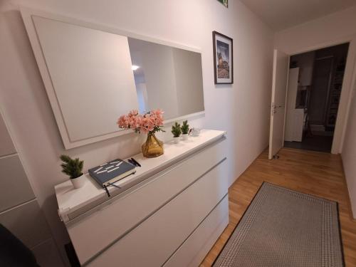 un corridoio con una cassettiera con specchio e fiori di La Chiave Boutique Apartment by Stefan Free Parking a Kalsdorf bei Graz