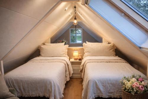 2 Betten in einem Dachzimmer mit Fenster in der Unterkunft B&B De Oase in Bergambacht