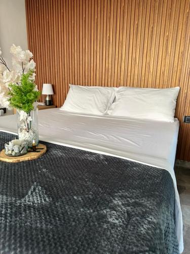 una camera da letto con un letto con lenzuola bianche e un vaso di fiori di Hotel Onsen a Guatapé