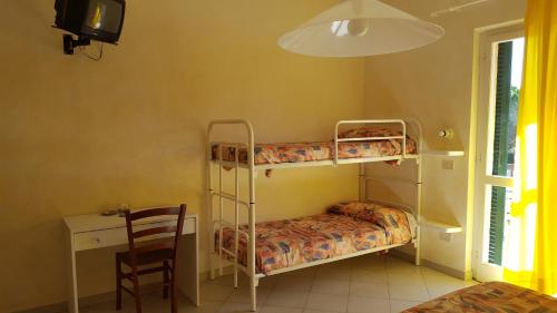 a room with two bunk beds and a desk at Hotel Villa Etrusca in Marina di Campo