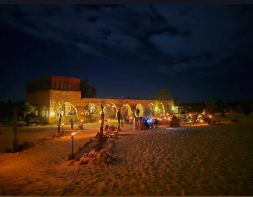 a building on a beach at night with lights at Hayaat siwa hot spring in Siwa