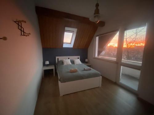 a bedroom with a bed and two windows at Stay with a View in Gdynia