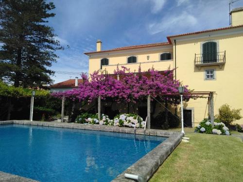 a house with a swimming pool and purple flowers at Casa de São João in Viana do Castelo